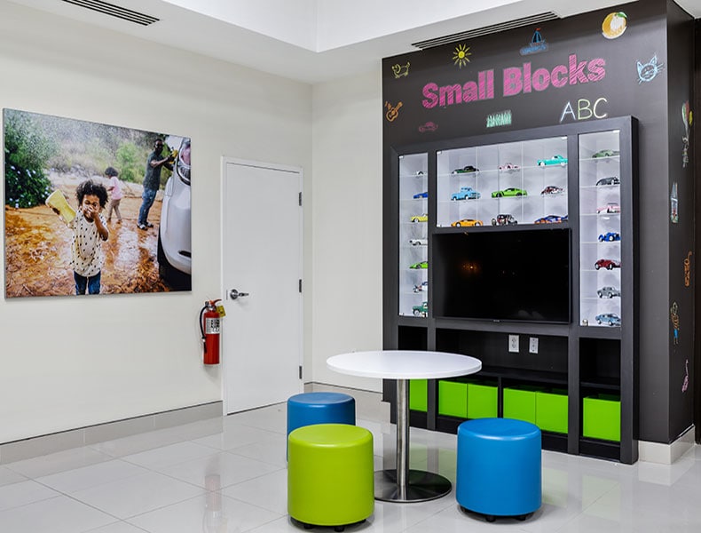 The kids' area of an EchoPark store has colorful blue and green seating and tables, with toy cars on display and children's books to keep the little ones occupied.