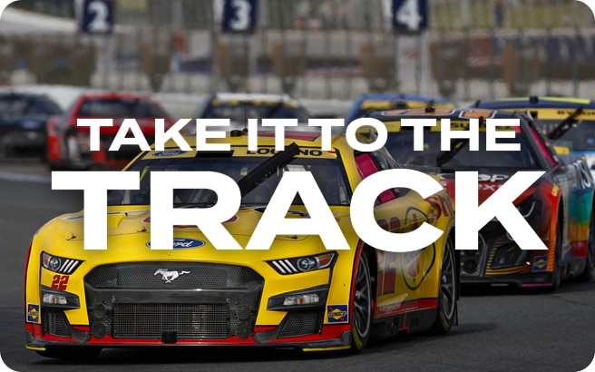 Race cars single file on Charlotte Motor Speedway track with NASCAR Driver Joey Lagano’s yellow Ford in front.