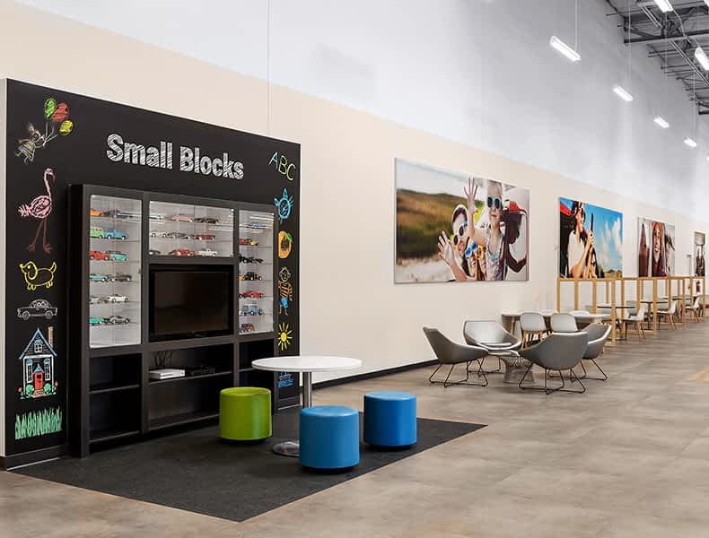 The kids' area of an EchoPark store has colorful blue and green seating and tables, with toy cars on display and children's books to keep the little ones occupied.