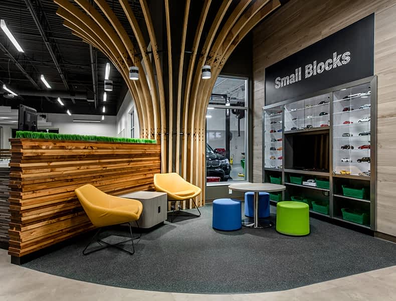 The kids' area of an EchoPark store has colorful blue and green seating and tables, with toy cars on display and children's books to keep the little ones occupied.