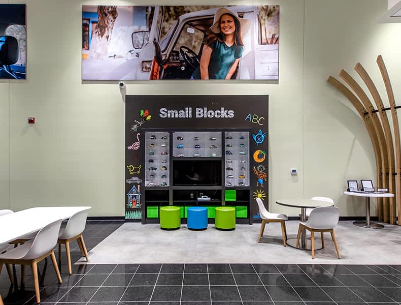 The kids' area of an EchoPark store has colorful blue and green seating and tables, with toy cars on display and children's books to keep the little ones occupied.