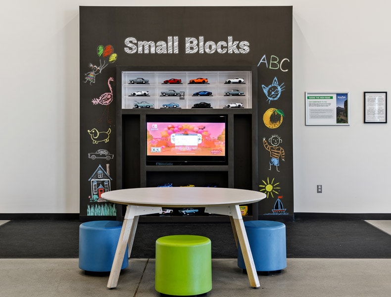 The kids' area of an EchoPark store has colorful blue and green seating and tables, with toy cars on display and children's books to keep the little ones occupied.