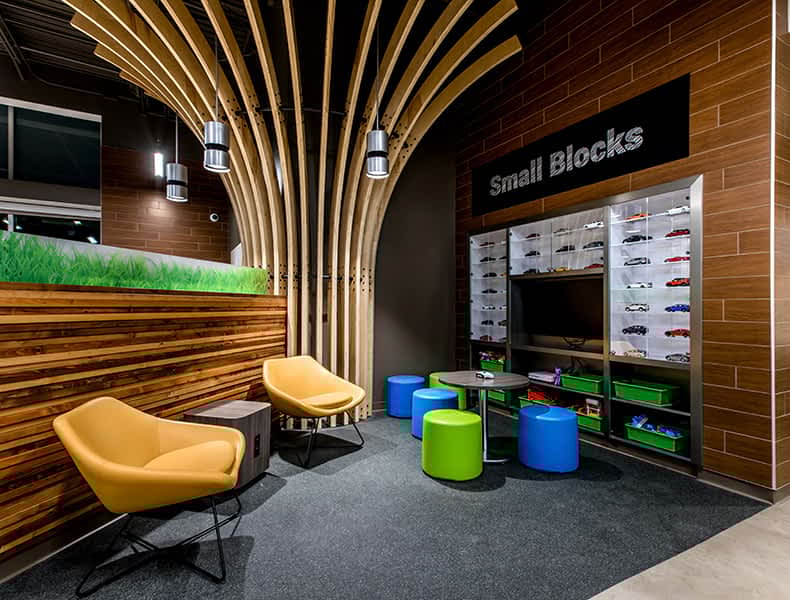 The kids' area of an EchoPark store has colorful blue and green seating and tables, with toy cars on display and children's books to keep the little ones occupied.