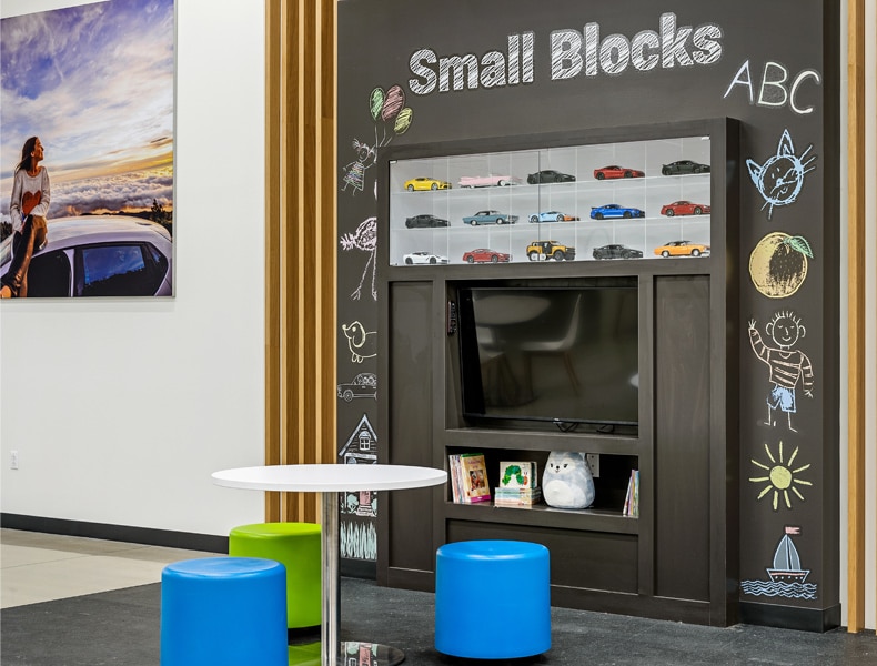 The kids' area of an EchoPark store has colorful blue and green seating and tables, with toy cars on display and children's books to keep the little ones occupied.