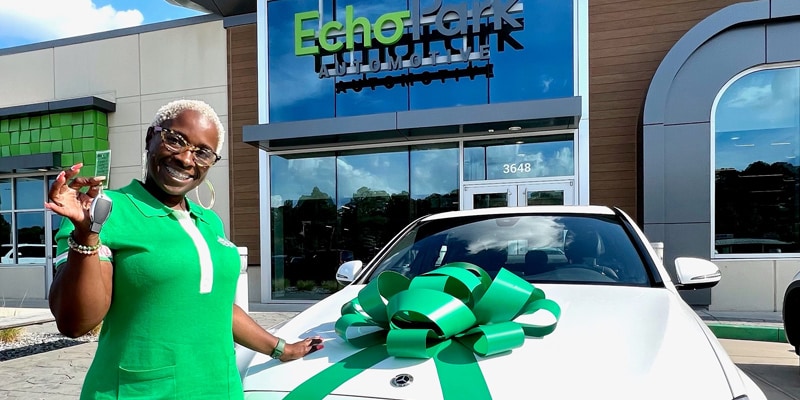 A woman named Kenya Morris stands in front of a white Mercedes-Benz sedan at EchoPark Charlotte.