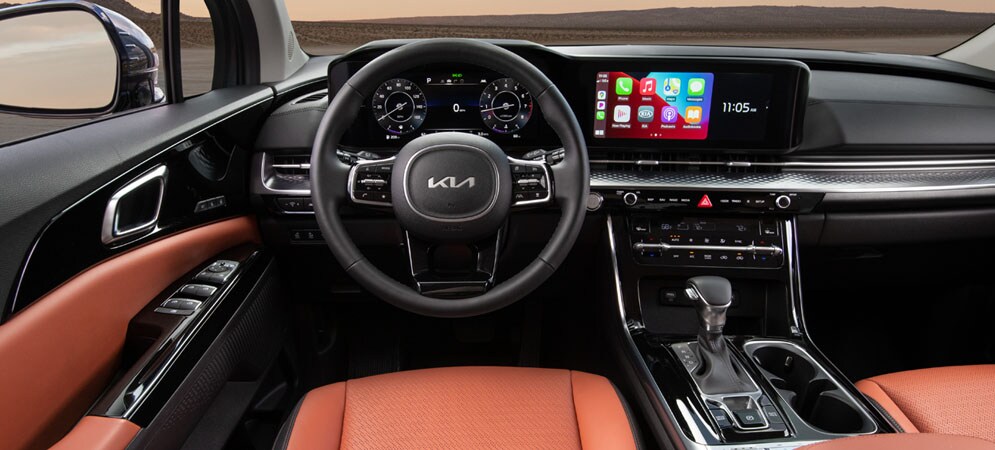 Image shows the steering wheel and dashboard of a Kia-Carnival highlighting the Apple car play display.