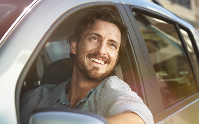 A man looking out of car with smile