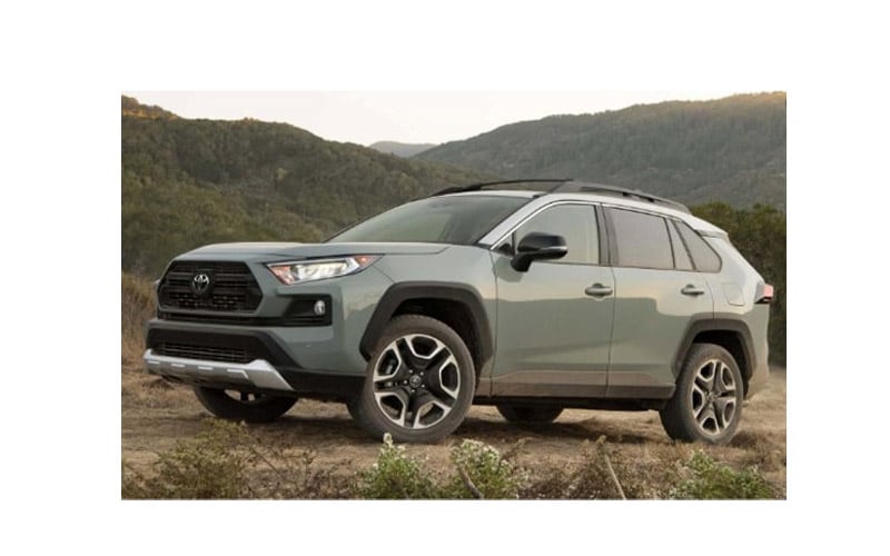 Image shows a light green Toyota RAV4 with a background of tree-covered mountains.