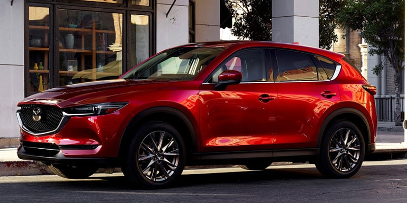 A composite image including a red Mazda CX-5 parked outside a city storefront and a red Honda CR-V parked on concrete in front of city office building.