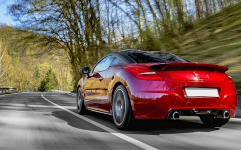 Image shows a red Audi TT coupe driving down a mountain highway.