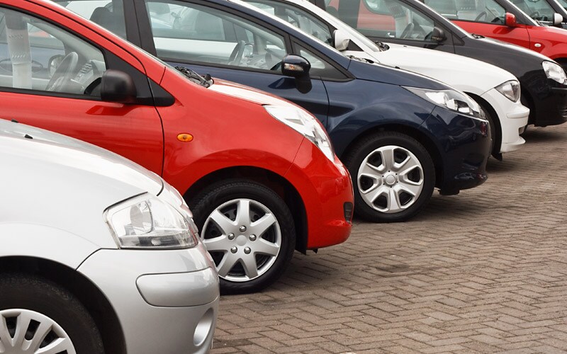 Image shows a lineup of cars in various colors at a dealership.